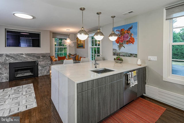 kitchen with pendant lighting, sink, kitchen peninsula, stainless steel dishwasher, and dark hardwood / wood-style floors