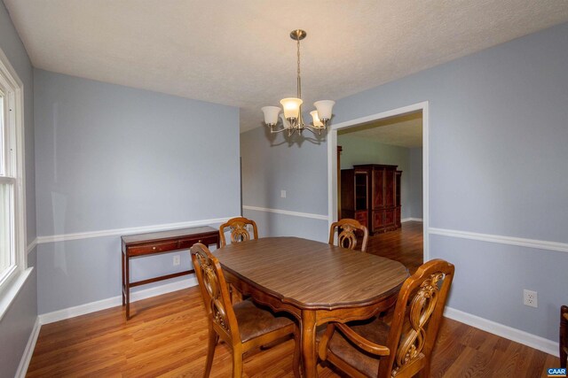 dining area featuring an inviting chandelier, a textured ceiling, and hardwood / wood-style floors