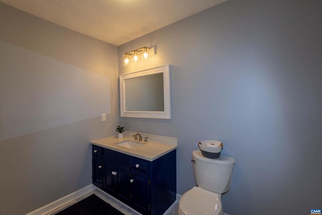 bathroom with a textured ceiling, vanity, and toilet