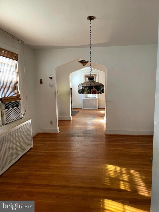 interior space with cooling unit, radiator heating unit, and hardwood / wood-style floors