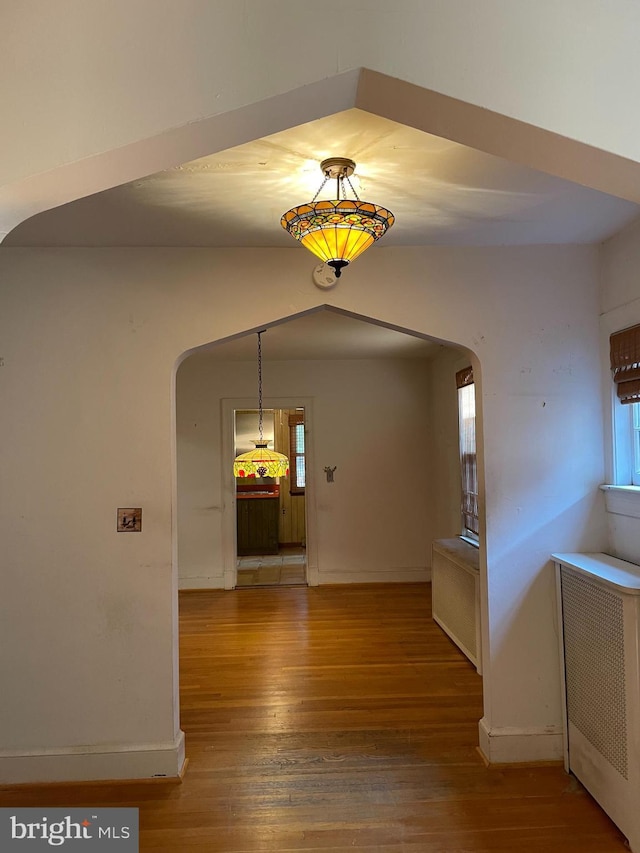 4527 S Dakota Ave NE, Washington, DC 20017 - unfurnished dining area featuring hardwood / wood-style flooring, radiator, arched walkways, and baseboards