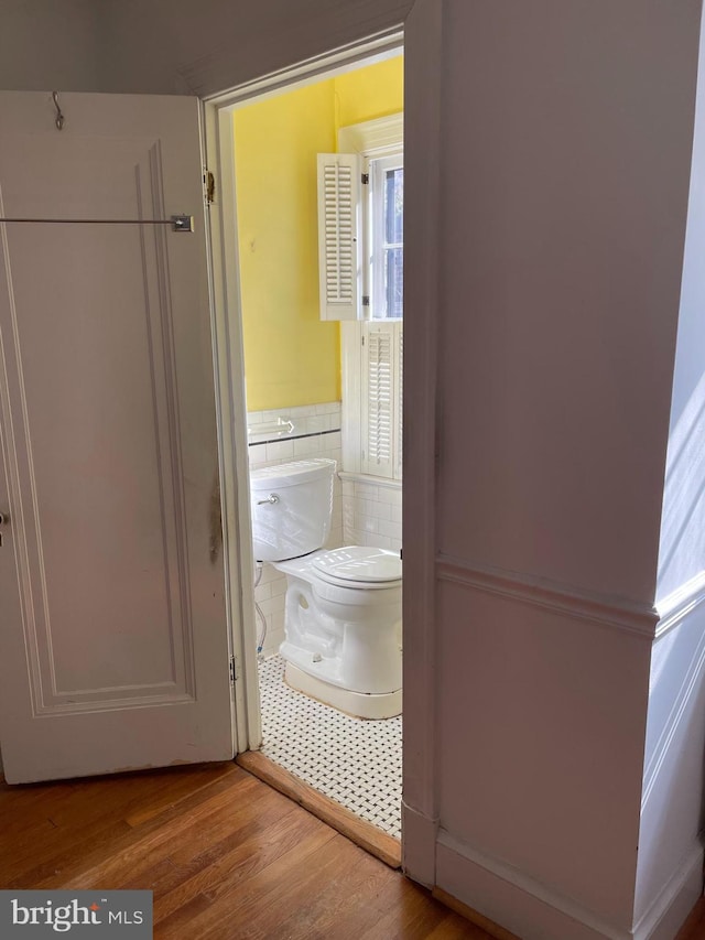 4527 S Dakota Ave NE, Washington, DC 20017 - bathroom featuring tile walls, wainscoting, wood finished floors, and toilet
