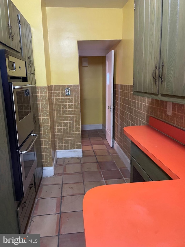 kitchen with double oven, tile walls, and light tile patterned flooring