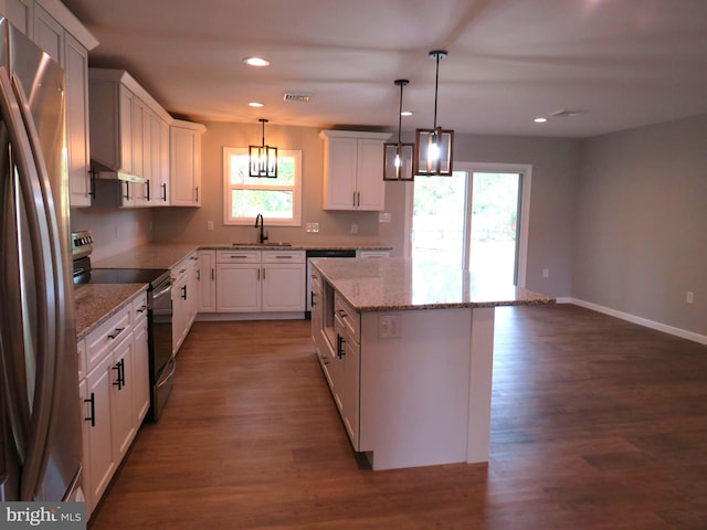 kitchen featuring appliances with stainless steel finishes, white cabinetry, a healthy amount of sunlight, and a kitchen island