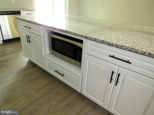 room details with appliances with stainless steel finishes, light stone countertops, white cabinetry, and dark hardwood / wood-style flooring