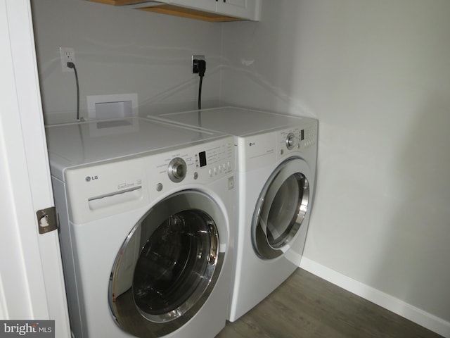 clothes washing area with washer and dryer and dark hardwood / wood-style flooring