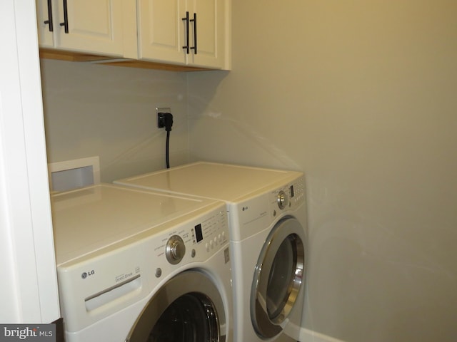 clothes washing area featuring cabinets and washer and dryer