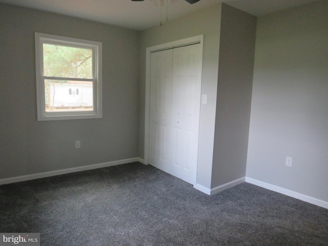 unfurnished bedroom with dark carpet, a closet, and ceiling fan