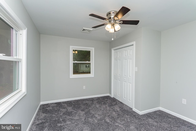 unfurnished bedroom featuring dark carpet, a closet, and ceiling fan