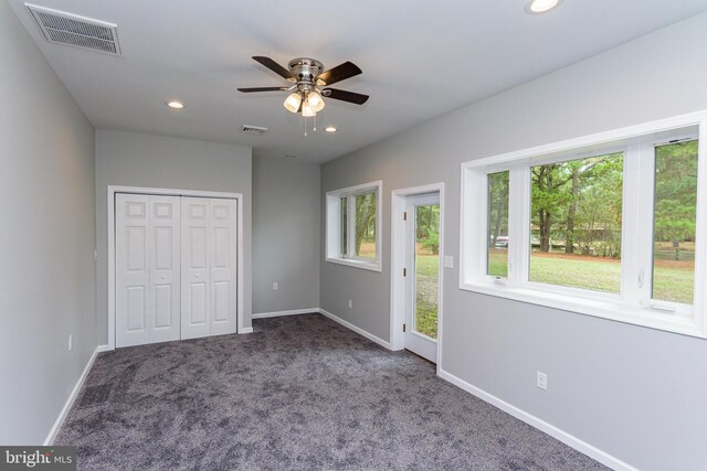 unfurnished bedroom with a closet, dark colored carpet, and ceiling fan