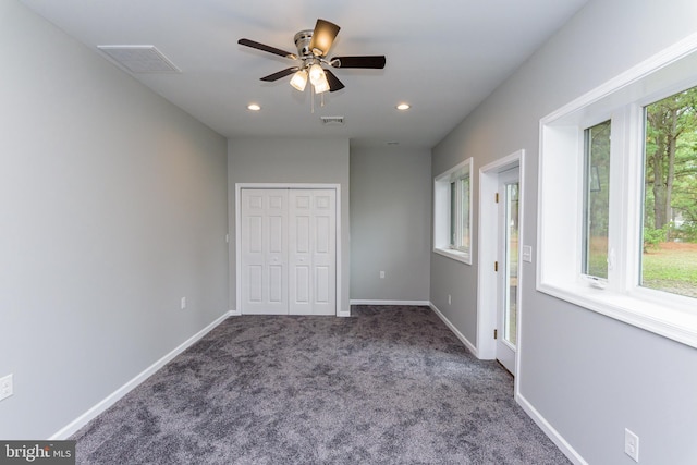 unfurnished bedroom with dark colored carpet, ceiling fan, and a closet