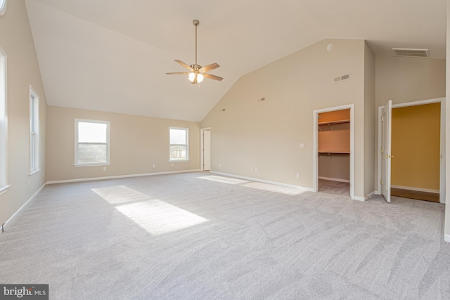 carpeted spare room with ceiling fan and high vaulted ceiling