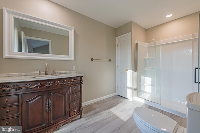 bathroom featuring hardwood / wood-style flooring, a shower with shower door, vanity, and toilet