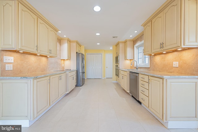 kitchen with decorative backsplash, stainless steel appliances, sink, and light stone countertops