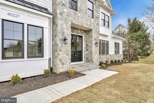 entrance to property featuring stone siding and a yard