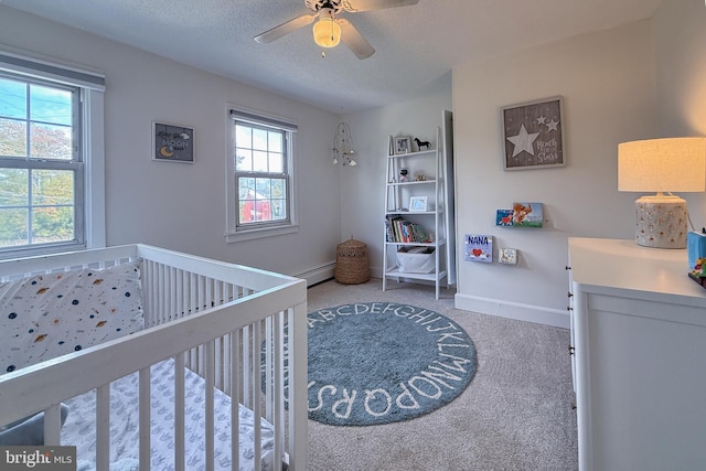 bedroom featuring a nursery area, carpet, multiple windows, and ceiling fan