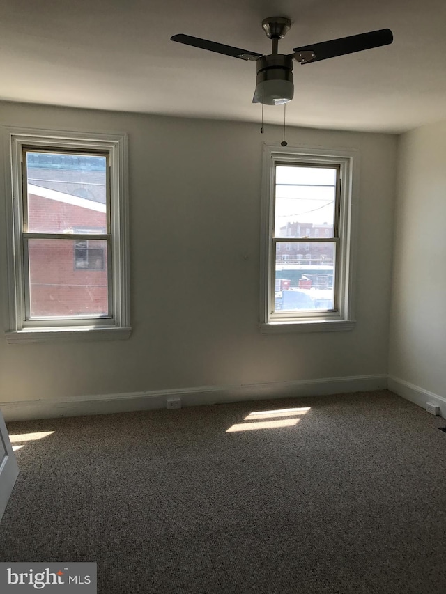 empty room featuring plenty of natural light, carpet floors, and ceiling fan