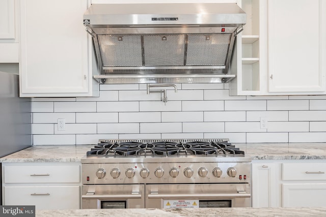 kitchen featuring white cabinets, light stone countertops, high end stainless steel range oven, and range hood