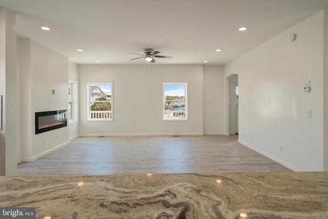 unfurnished living room with light wood-type flooring and ceiling fan