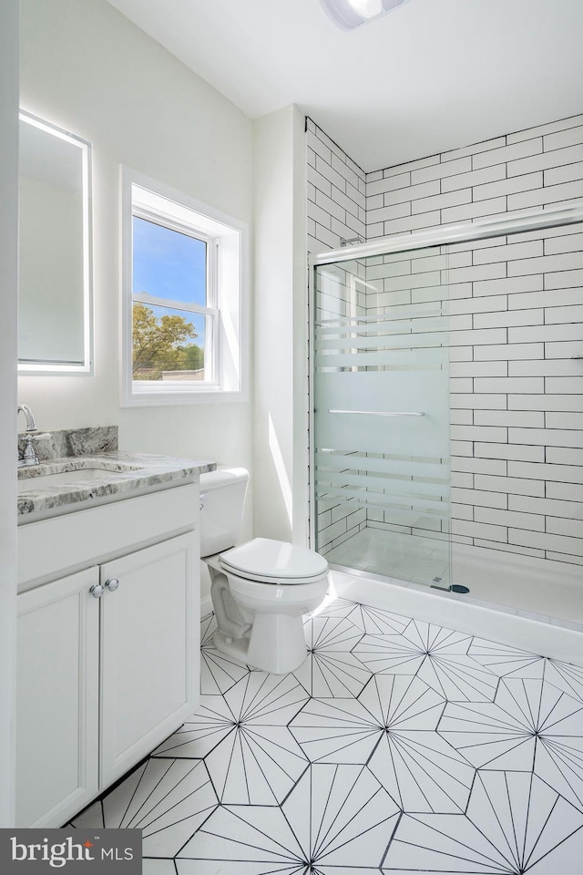 bathroom with tile patterned flooring, vanity, toilet, and a shower with shower door