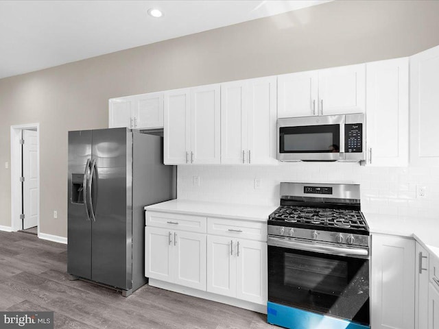 kitchen featuring stainless steel appliances, white cabinets, light hardwood / wood-style floors, and tasteful backsplash