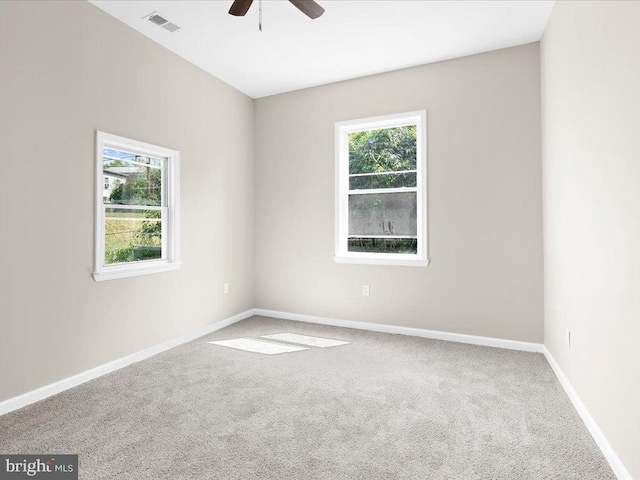 carpeted spare room with ceiling fan and plenty of natural light