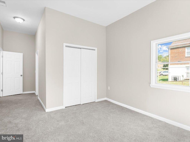 unfurnished bedroom with light colored carpet and a closet