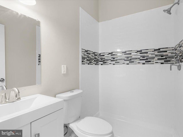 bathroom with vanity, toilet, and tiled shower