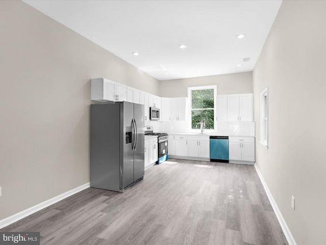 kitchen with white cabinets, sink, stainless steel appliances, light wood-type flooring, and decorative backsplash