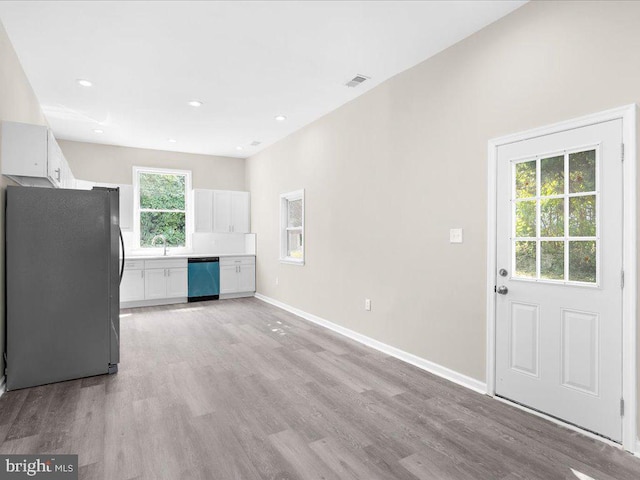 kitchen with white cabinets, stainless steel appliances, light hardwood / wood-style flooring, and a healthy amount of sunlight