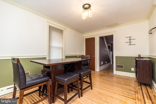 dining space with crown molding, light hardwood / wood-style floors, and baseboard heating