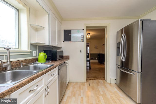 kitchen featuring white cabinets, ornamental molding, sink, light hardwood / wood-style flooring, and stainless steel appliances