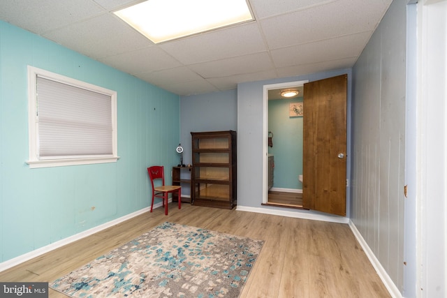 living area featuring a drop ceiling and hardwood / wood-style flooring