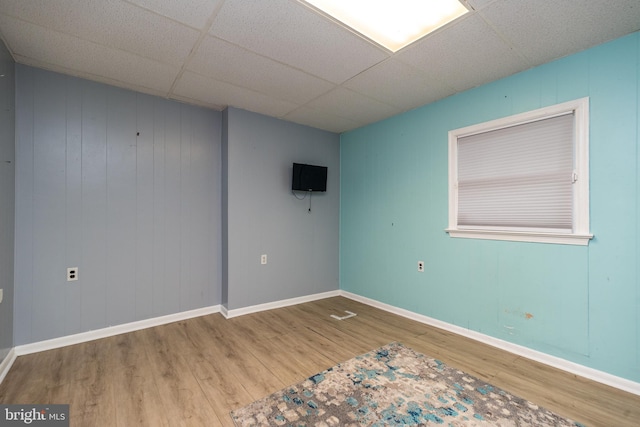 spare room featuring wood walls, a paneled ceiling, and hardwood / wood-style floors