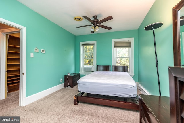 carpeted bedroom with ceiling fan, cooling unit, a baseboard heating unit, and a walk in closet