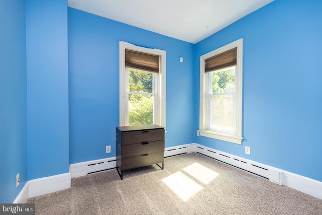 empty room with a baseboard heating unit, light colored carpet, and plenty of natural light