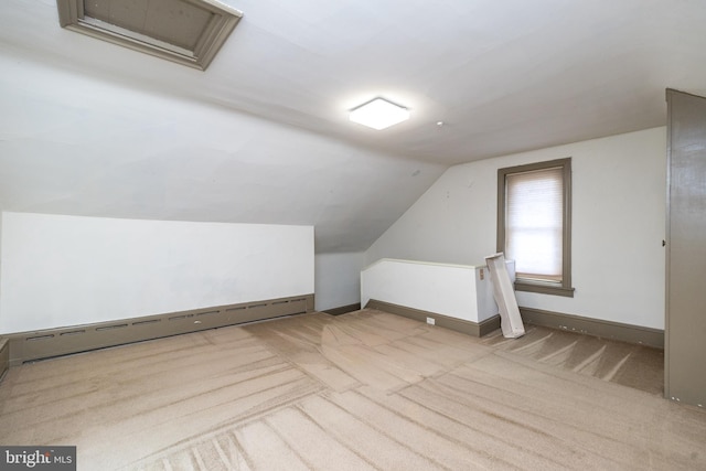 additional living space with vaulted ceiling, baseboard heating, and light carpet