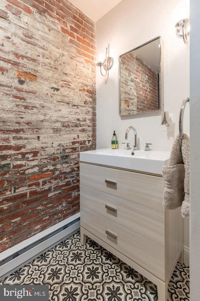 bathroom featuring brick wall, vanity, tile patterned flooring, and a baseboard heating unit