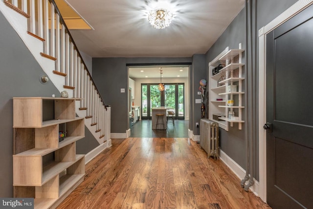 foyer entrance with radiator, hardwood / wood-style flooring, and a notable chandelier