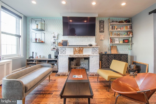 living room featuring radiator heating unit, a brick fireplace, and hardwood / wood-style flooring