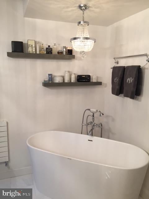 bathroom featuring a notable chandelier, radiator, and a tub