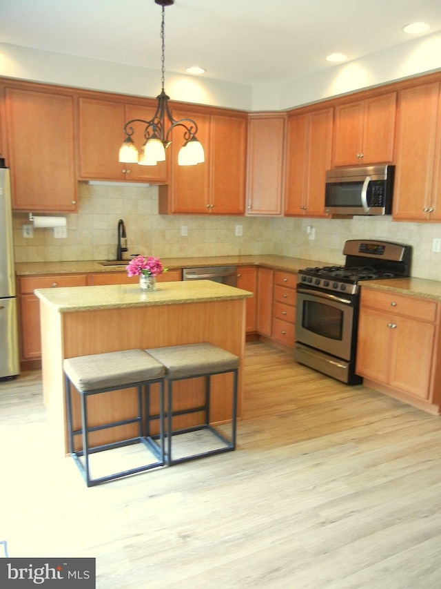 kitchen featuring an inviting chandelier, appliances with stainless steel finishes, a center island, and light hardwood / wood-style flooring