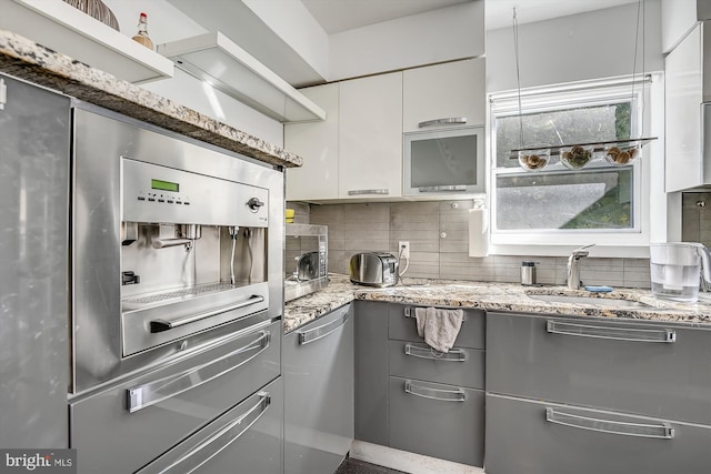 kitchen with light stone counters, white cabinets, stainless steel appliances, and tasteful backsplash