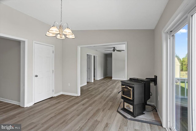 dining area featuring ceiling fan with notable chandelier, a wood stove, lofted ceiling, and wood-type flooring