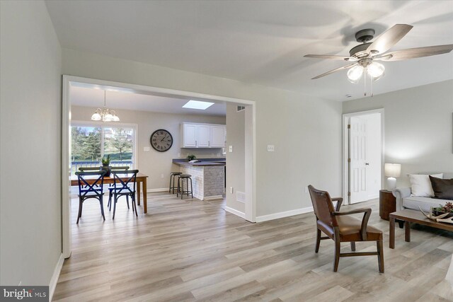 empty room with ceiling fan with notable chandelier, light hardwood / wood-style flooring, and a wood stove