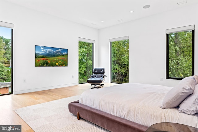 bedroom with hardwood / wood-style flooring, access to exterior, and multiple windows