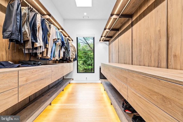 walk in closet with a skylight and light wood-type flooring