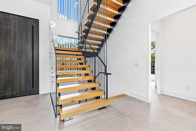 stairway featuring a towering ceiling and concrete floors