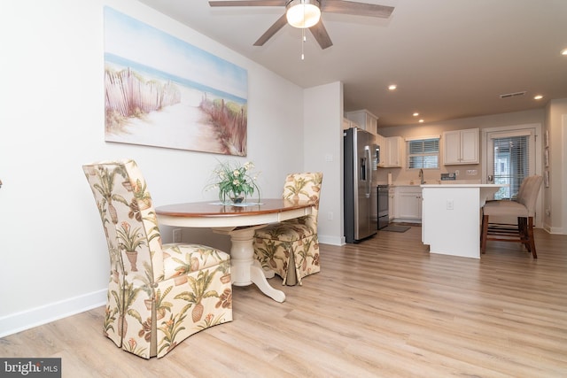 dining space with ceiling fan, light hardwood / wood-style flooring, and sink