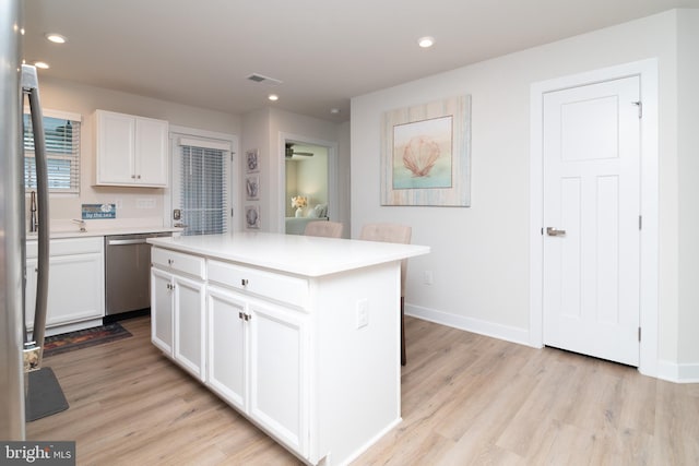 kitchen featuring light wood-type flooring, a center island, stainless steel dishwasher, and white cabinetry